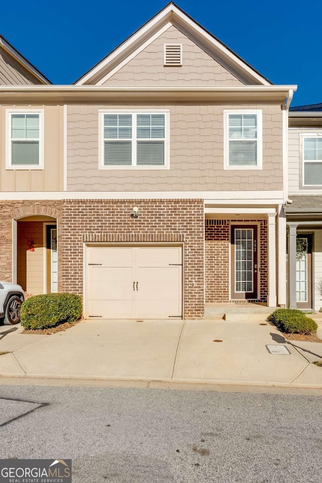 townhome / multi-family property featuring a garage, concrete driveway, and brick siding