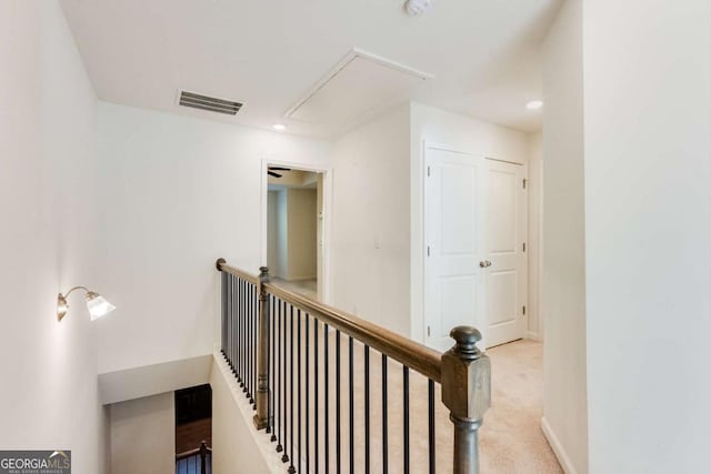 hallway featuring attic access, visible vents, baseboards, an upstairs landing, and carpet floors