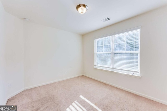 carpeted empty room featuring visible vents and baseboards