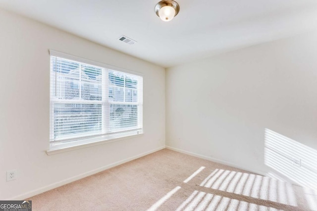 empty room featuring carpet flooring, visible vents, and baseboards