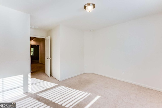 unfurnished room featuring baseboards and light colored carpet