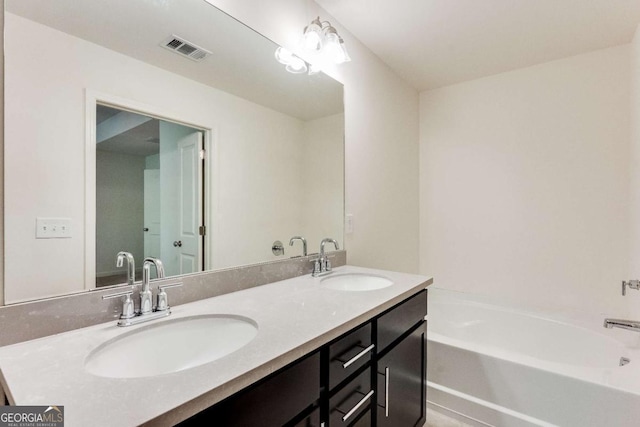 bathroom featuring double vanity, a sink, visible vents, and a tub