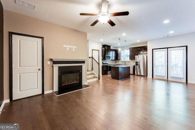 unfurnished living room with dark wood-style floors, recessed lighting, visible vents, a ceiling fan, and a glass covered fireplace