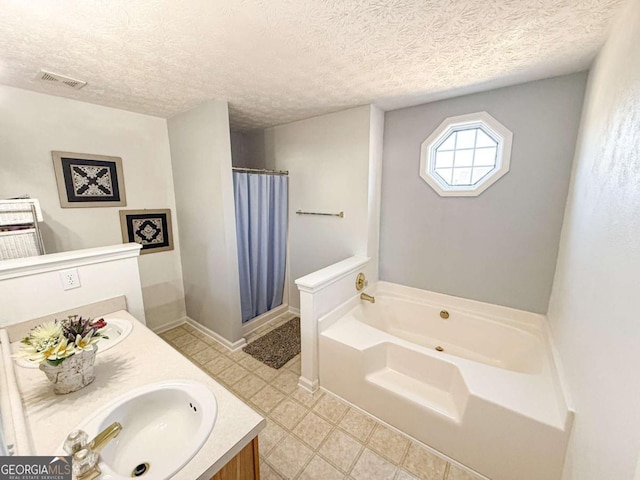 bathroom with a textured ceiling, vanity, visible vents, and a bath