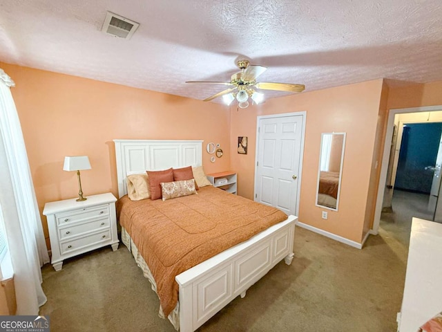 carpeted bedroom with a textured ceiling, a ceiling fan, visible vents, and baseboards