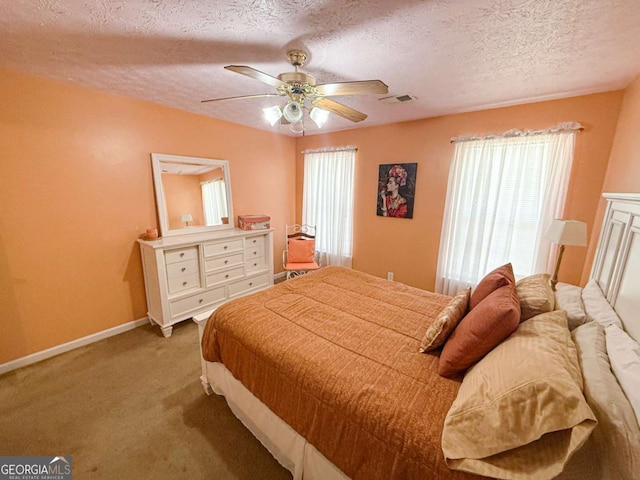 carpeted bedroom featuring a ceiling fan, visible vents, a textured ceiling, and baseboards