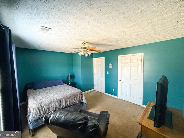 carpeted bedroom with visible vents, a textured ceiling, a ceiling fan, and baseboards