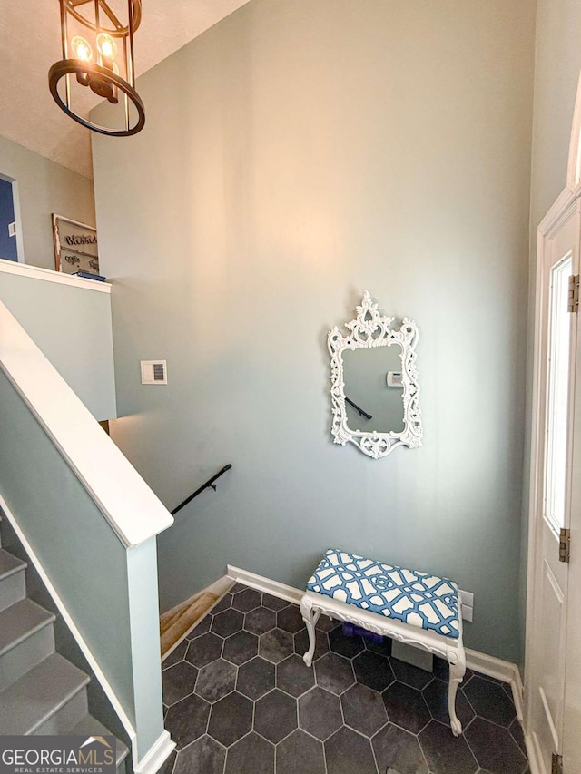 staircase with a healthy amount of sunlight, baseboards, and a notable chandelier