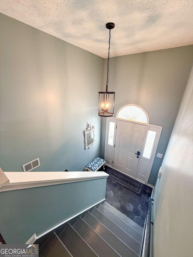 entrance foyer featuring a textured ceiling, dark wood finished floors, and visible vents