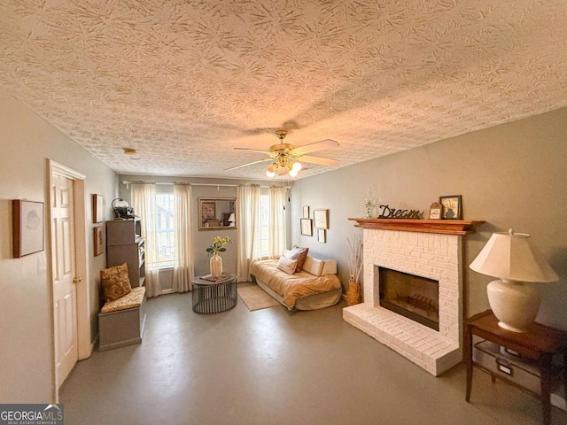 living area with finished concrete floors, a fireplace, a textured ceiling, and ceiling fan