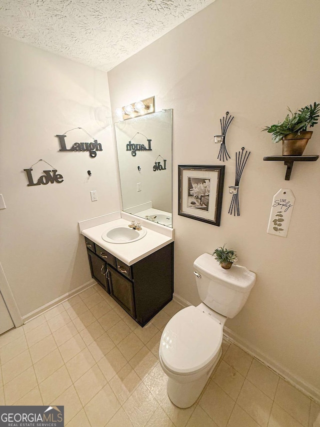 bathroom featuring baseboards, toilet, tile patterned floors, a textured ceiling, and vanity