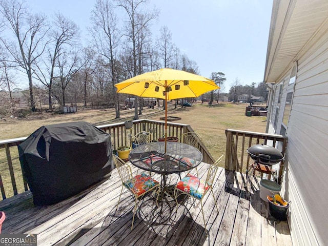 wooden terrace featuring grilling area, a lawn, and outdoor dining space