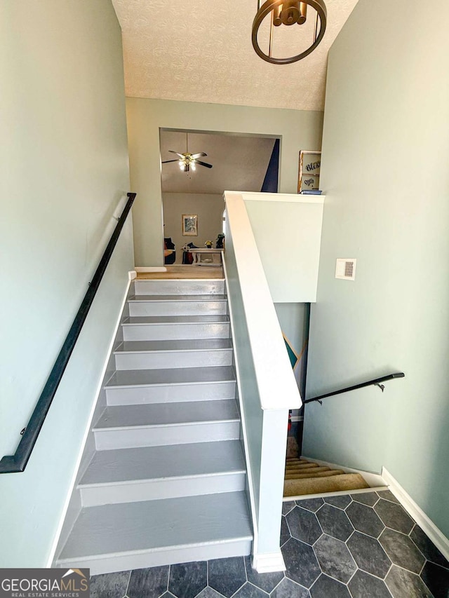 stairs featuring visible vents, a ceiling fan, and a textured ceiling