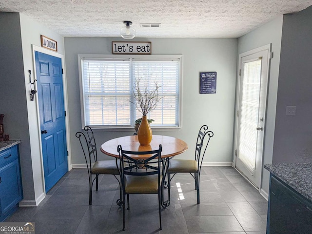 dining room featuring a textured ceiling, visible vents, and baseboards