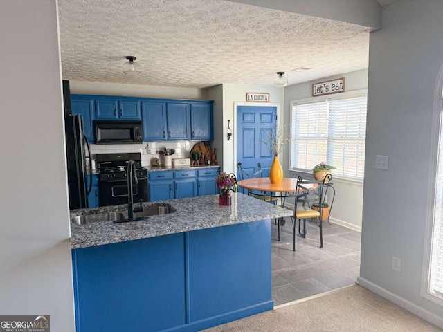 kitchen featuring baseboards, a peninsula, blue cabinetry, black appliances, and a sink