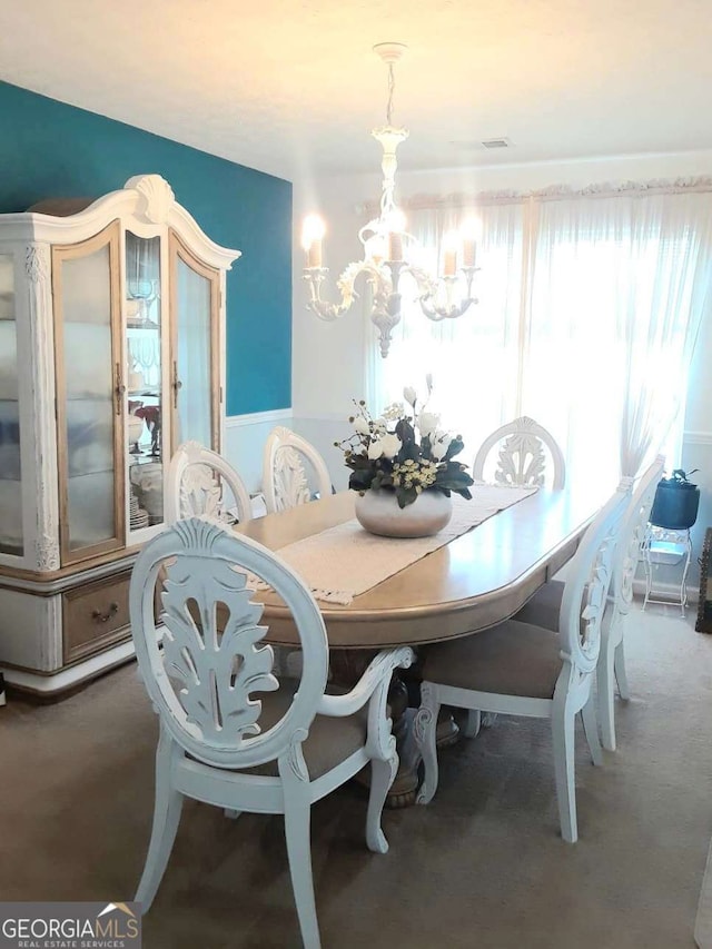 carpeted dining space featuring a chandelier