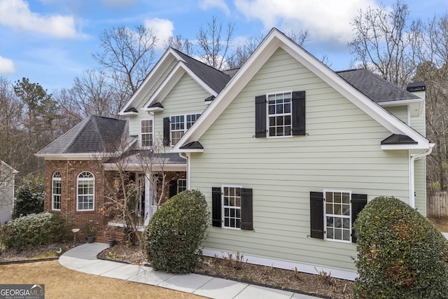 traditional-style home featuring brick siding and a shingled roof