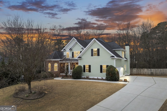 traditional-style house featuring a garage, driveway, and a chimney