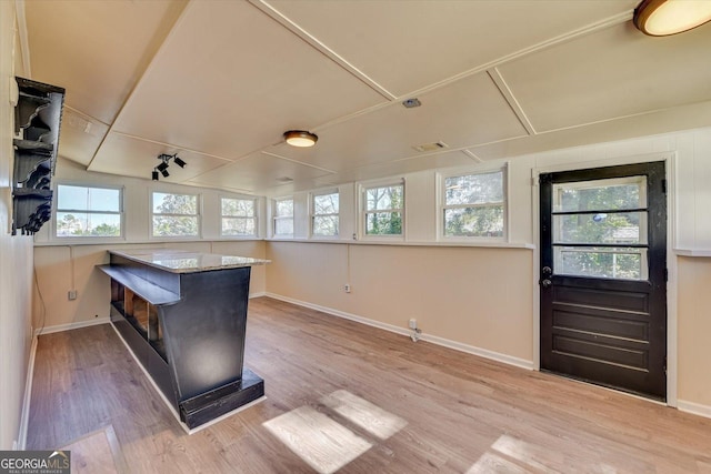 kitchen featuring a healthy amount of sunlight, a peninsula, baseboards, and wood finished floors