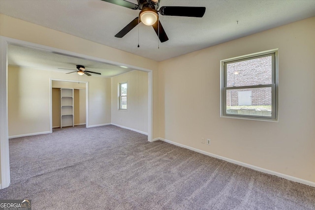 carpeted empty room with a textured ceiling and baseboards