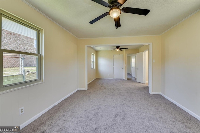 spare room featuring baseboards, a textured ceiling, ornamental molding, and carpet flooring