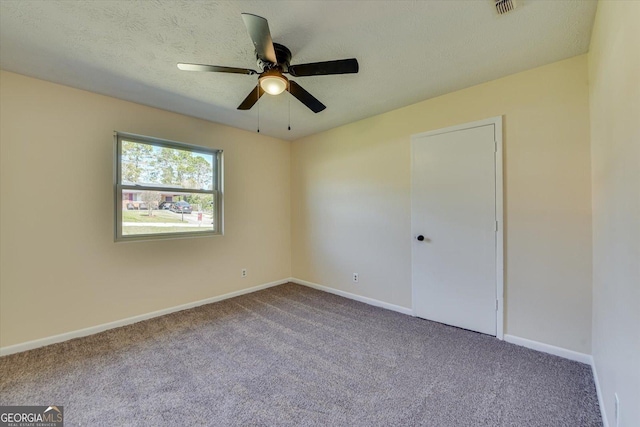 carpeted empty room featuring a ceiling fan, a textured ceiling, and baseboards