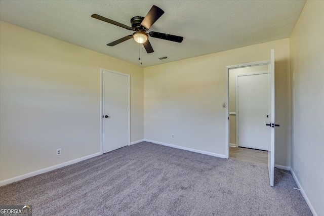 unfurnished bedroom with carpet floors, visible vents, a textured ceiling, and baseboards