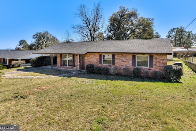 view of front facade with brick siding, a front yard, fence, a carport, and driveway