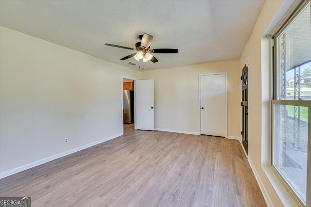 unfurnished bedroom with light wood finished floors, visible vents, baseboards, and freestanding refrigerator