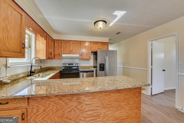 kitchen with under cabinet range hood, a peninsula, a sink, ornamental molding, and appliances with stainless steel finishes