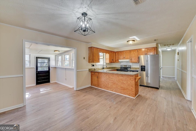 kitchen featuring brown cabinets, a peninsula, stainless steel appliances, a textured ceiling, and light wood-style floors