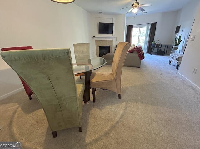 dining area featuring carpet floors, baseboards, ceiling fan, and a tiled fireplace