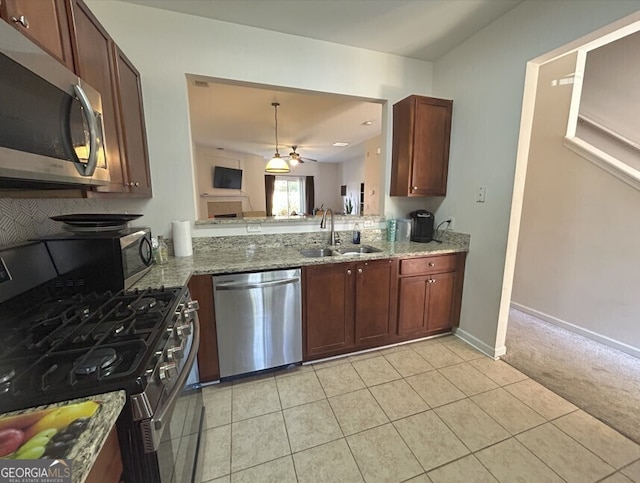 kitchen featuring stainless steel appliances, light stone counters, a fireplace, and a sink