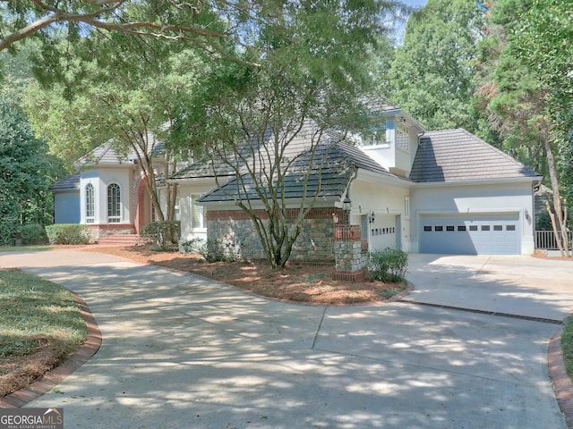 view of front of home featuring driveway, a tile roof, a garage, and stucco siding