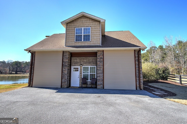 view of front of house featuring aphalt driveway, stone siding, and a shingled roof