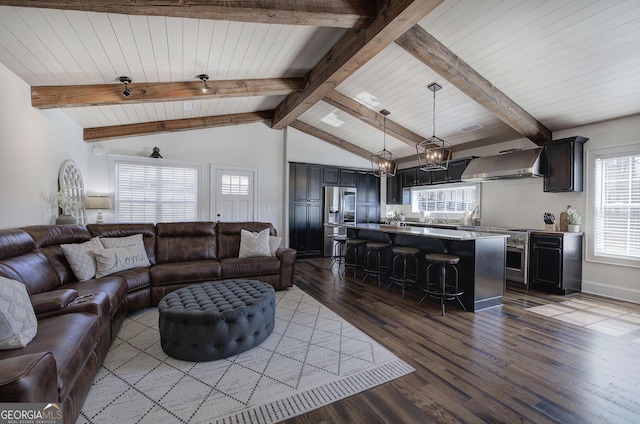 living area with lofted ceiling with beams, an inviting chandelier, and wood finished floors