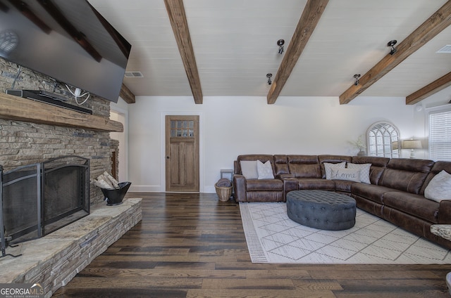 living area featuring a stone fireplace, lofted ceiling with beams, wood finished floors, and visible vents