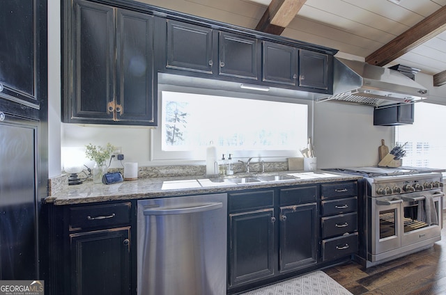 kitchen featuring range hood, beam ceiling, blue cabinetry, dark wood-style flooring, and appliances with stainless steel finishes