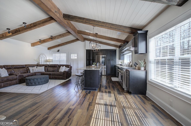 living room with lofted ceiling with beams, a healthy amount of sunlight, and dark wood-style floors