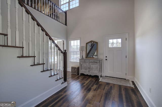 foyer entrance with stairway, a high ceiling, baseboards, and wood finished floors