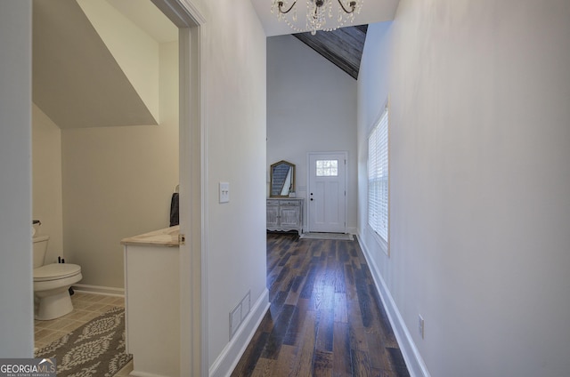 hall with visible vents, baseboards, a chandelier, wood finished floors, and high vaulted ceiling