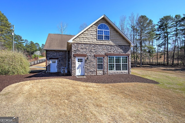 view of front of house with stone siding, a front lawn, and fence