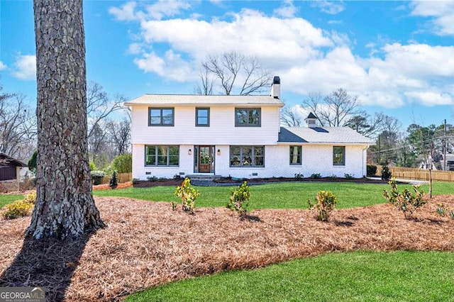 colonial home with crawl space, brick siding, a chimney, and a front yard