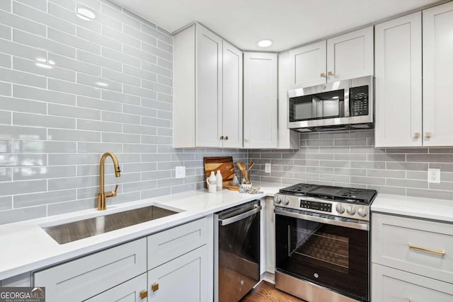 kitchen with stainless steel appliances, a sink, light countertops, and decorative backsplash