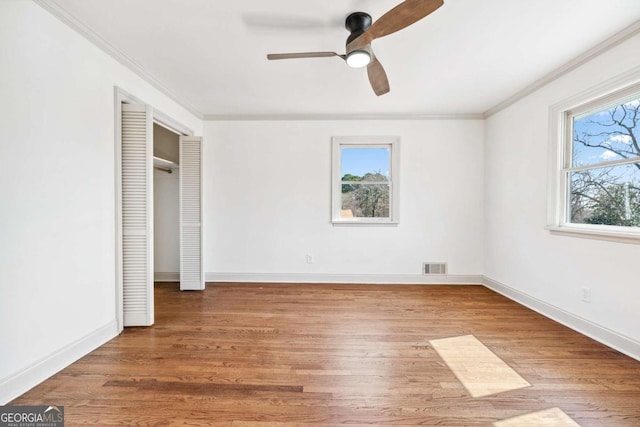 unfurnished bedroom with baseboards, wood finished floors, visible vents, and crown molding