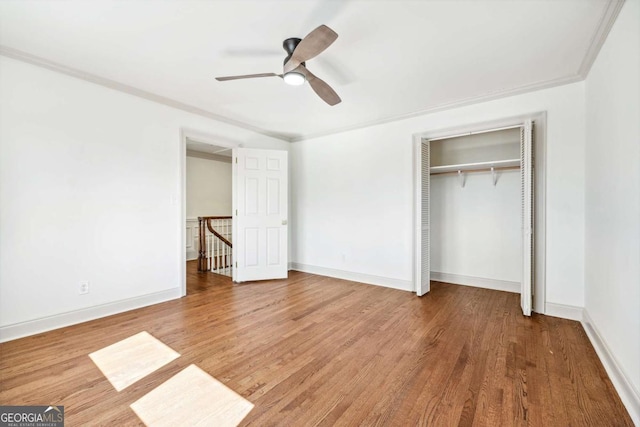 unfurnished bedroom with a closet, crown molding, baseboards, and wood finished floors