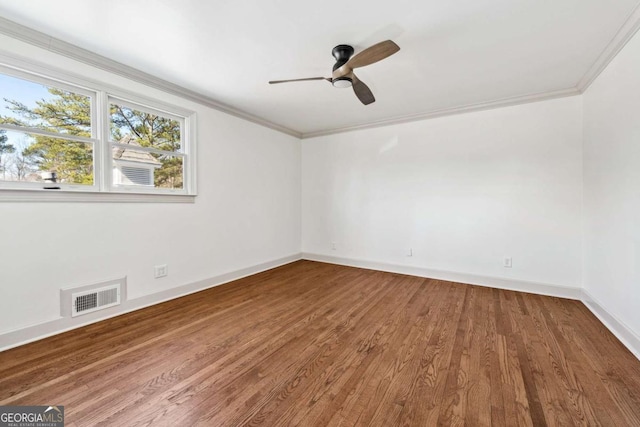 empty room featuring visible vents, ornamental molding, ceiling fan, wood finished floors, and baseboards