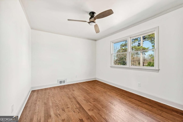 unfurnished room with crown molding, visible vents, ceiling fan, wood finished floors, and baseboards