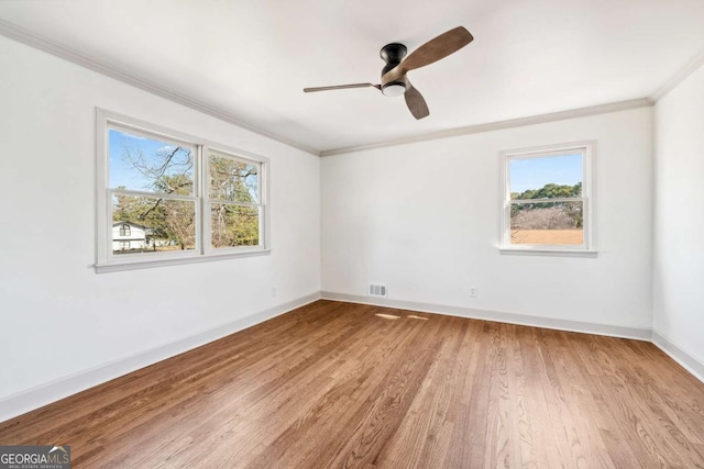 spare room featuring baseboards, light wood finished floors, visible vents, and crown molding