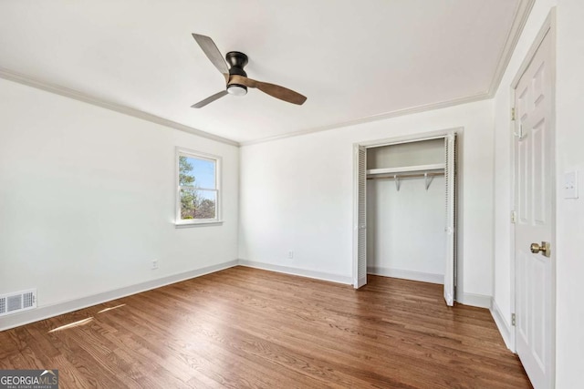 unfurnished bedroom featuring ornamental molding, visible vents, baseboards, and wood finished floors